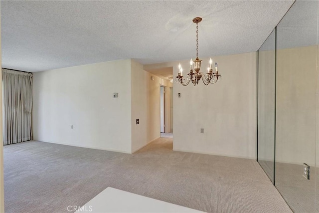 empty room with a chandelier, carpet floors, and a textured ceiling