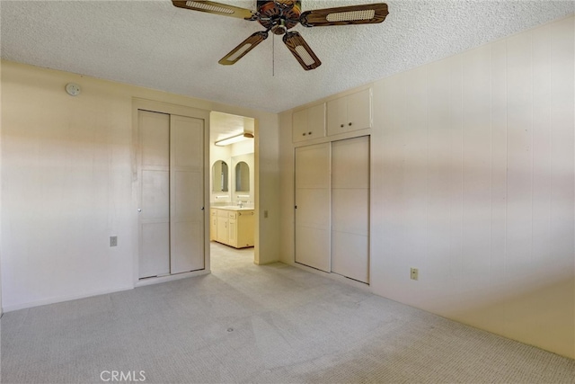 unfurnished bedroom featuring light carpet, a textured ceiling, ensuite bath, and a sink