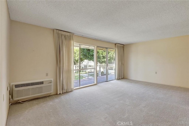 spare room with carpet floors, a textured ceiling, and an AC wall unit