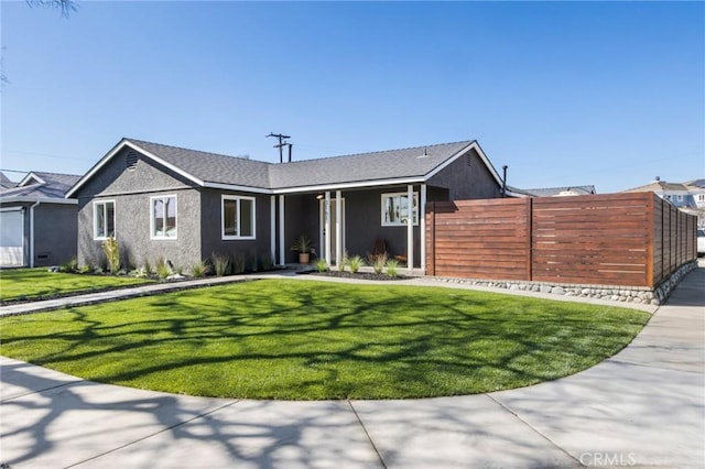 view of front facade with stucco siding, a front lawn, and fence