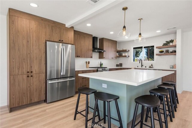 kitchen with stainless steel fridge, a breakfast bar area, wall chimney range hood, and open shelves