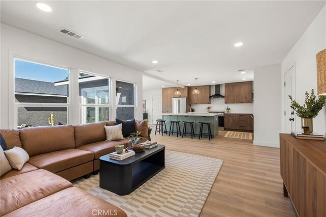 living area with recessed lighting, visible vents, baseboards, and light wood finished floors