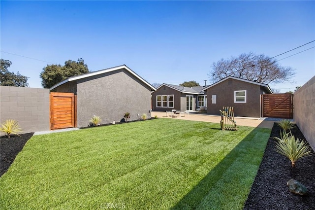 back of house featuring stucco siding, a fenced backyard, and a gate