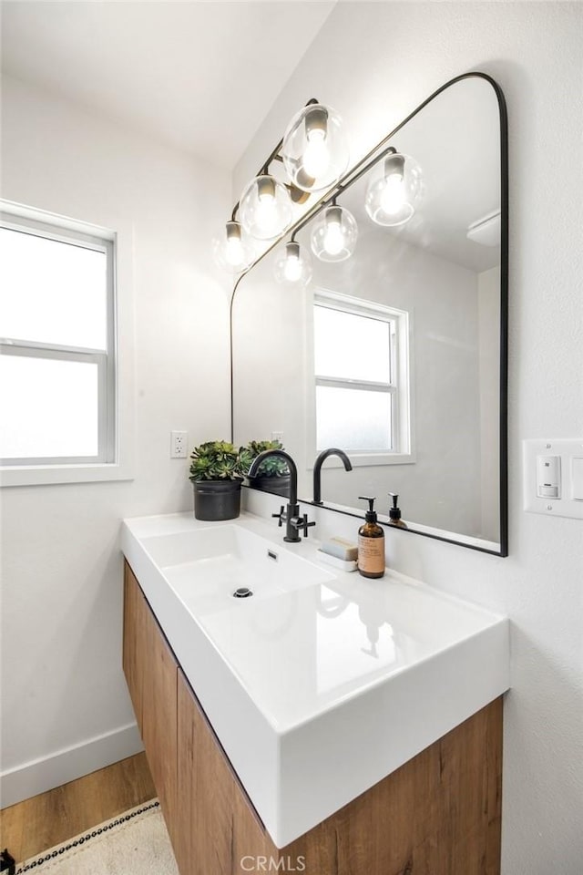 bathroom with vanity, wood finished floors, and baseboards