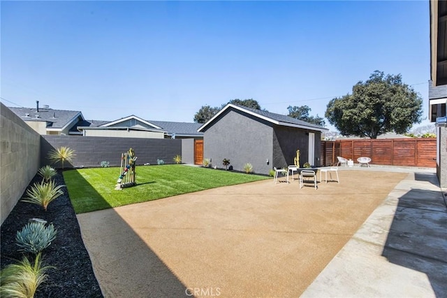 back of house featuring a yard, a patio area, a fenced backyard, and stucco siding