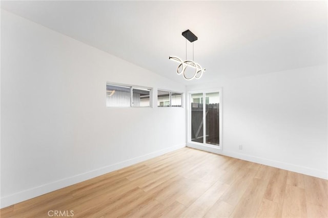 spare room with a chandelier, baseboards, light wood-style floors, and vaulted ceiling