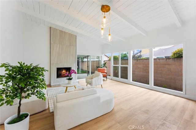 sunroom / solarium with lofted ceiling with beams, wooden ceiling, and a large fireplace