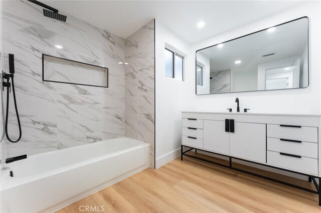 full bath with baseboards, shower / bath combination, recessed lighting, wood finished floors, and vanity