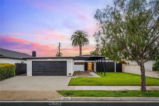 mid-century home featuring an attached garage, driveway, a yard, and fence