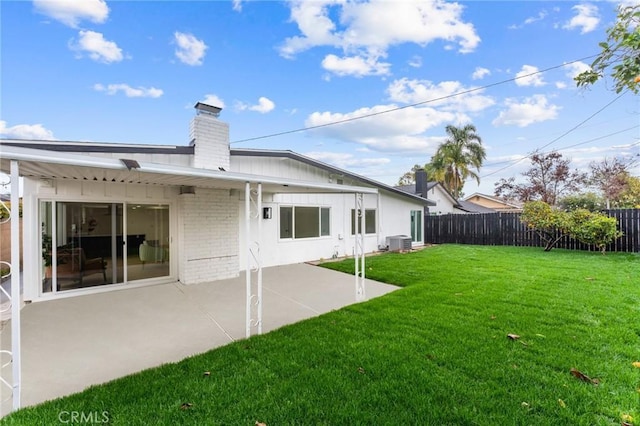 back of house with central AC, a fenced backyard, a yard, brick siding, and a patio area