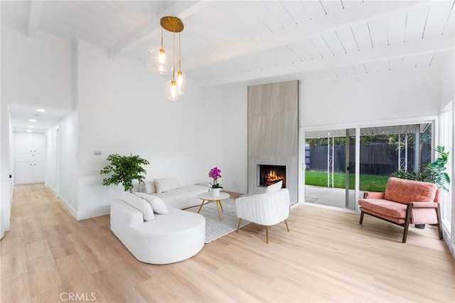 living room with beamed ceiling, light wood-style flooring, a fireplace, baseboards, and wood ceiling