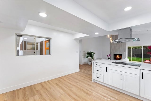 kitchen with a large fireplace, recessed lighting, light wood-style floors, white cabinets, and wall chimney exhaust hood