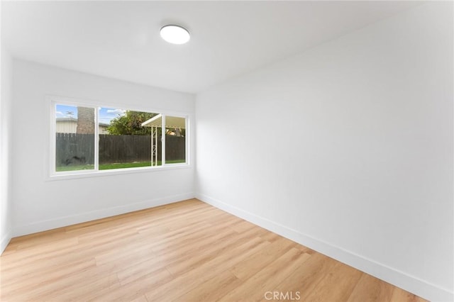 spare room with baseboards and light wood-style flooring