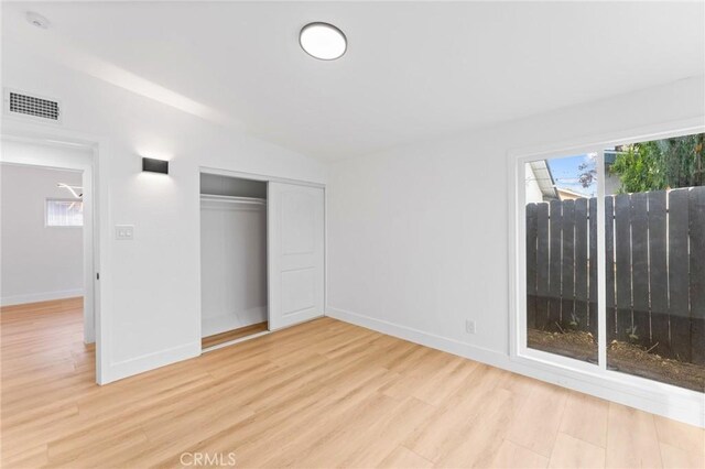 unfurnished bedroom with baseboards, visible vents, a closet, and light wood-type flooring