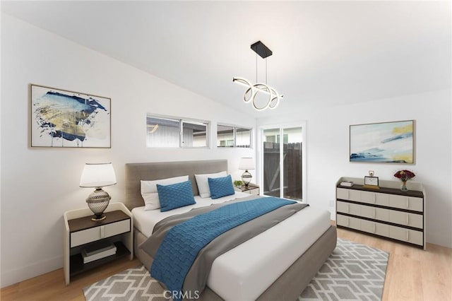 bedroom with light wood-type flooring, a notable chandelier, and vaulted ceiling