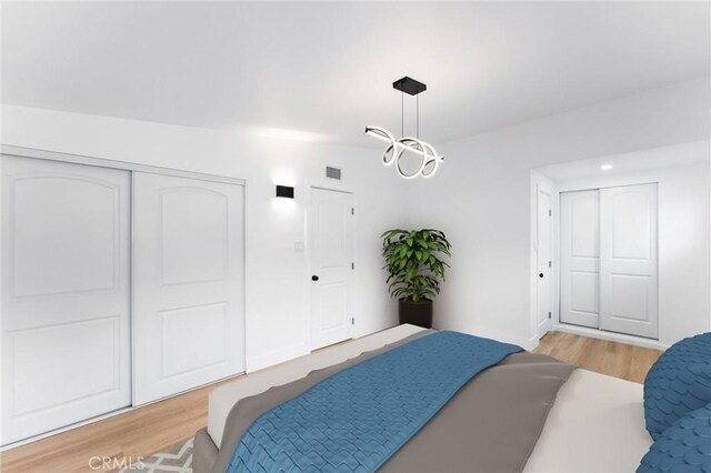 bedroom with light wood-style flooring, a notable chandelier, visible vents, and a closet