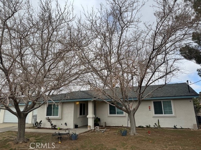 ranch-style home with a garage, roof with shingles, and stucco siding