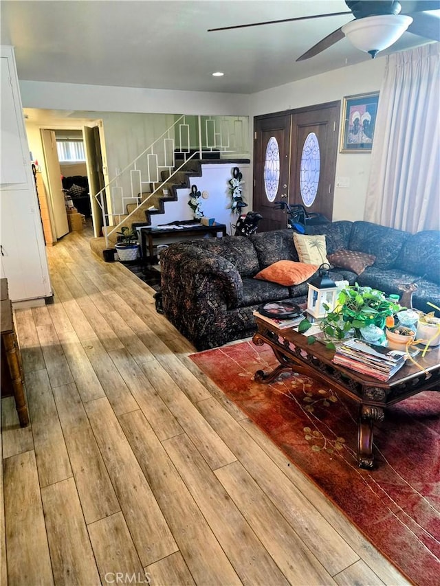 living room featuring plenty of natural light, stairs, a ceiling fan, and hardwood / wood-style floors