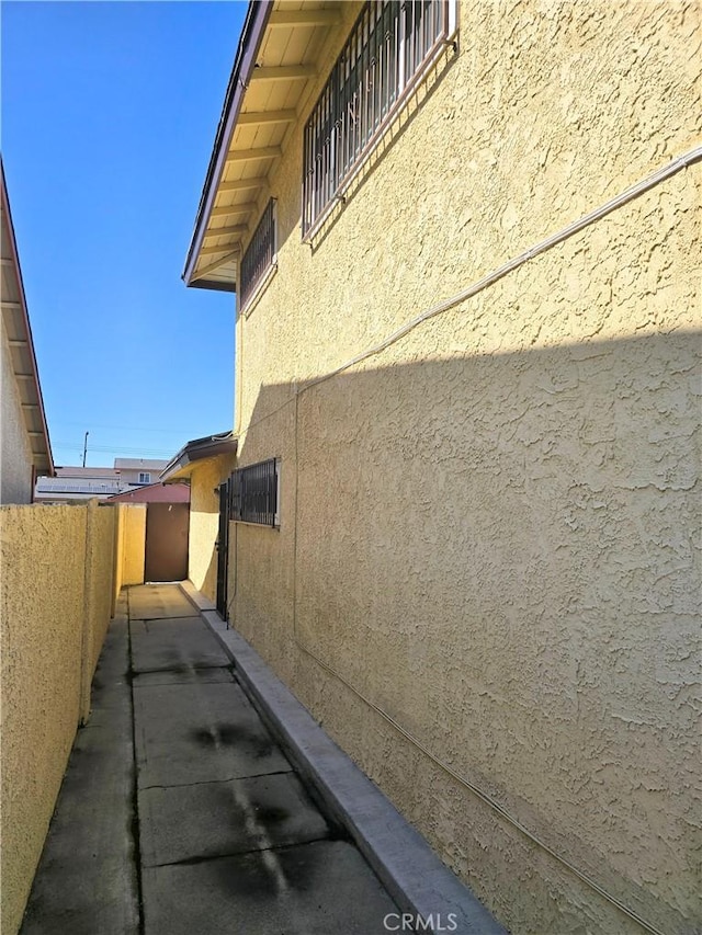 view of property exterior with stucco siding and fence