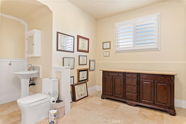 bathroom with toilet, baseboards, and a sink