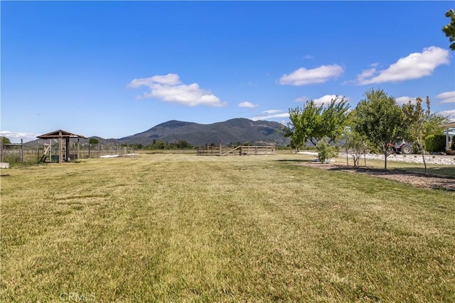 view of yard with fence, a rural view, and a mountain view