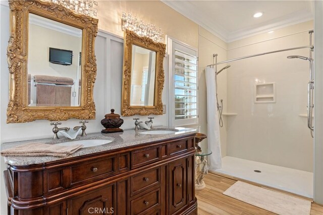 full bath featuring ornamental molding, wood finished floors, a stall shower, and a sink