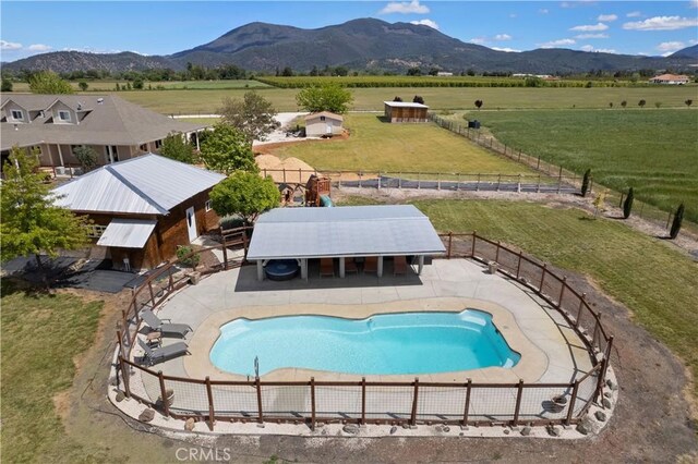 view of pool featuring a patio area, a mountain view, a rural view, and fence