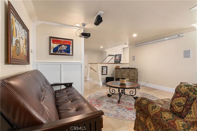 living area featuring wainscoting, a decorative wall, and recessed lighting