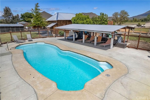 view of swimming pool featuring a patio, a fenced in pool, fence, a mountain view, and outdoor dry bar