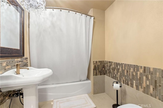 bathroom featuring shower / bath combo with shower curtain and tile walls