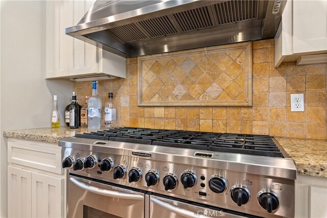 kitchen with backsplash, light stone countertops, double oven range, custom range hood, and white cabinetry