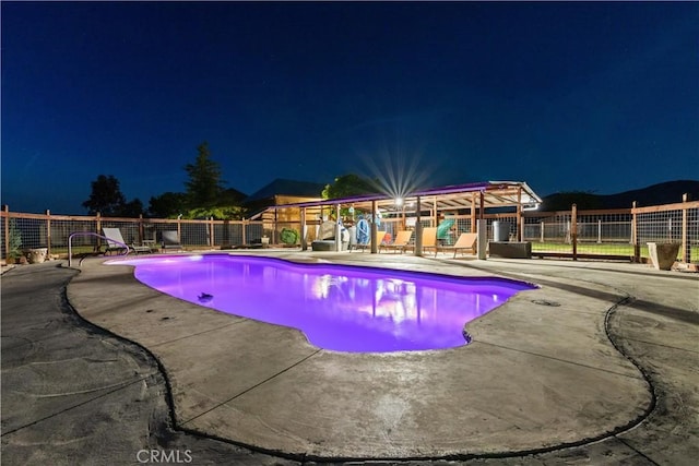 pool at twilight with a fenced in pool, a patio, and fence