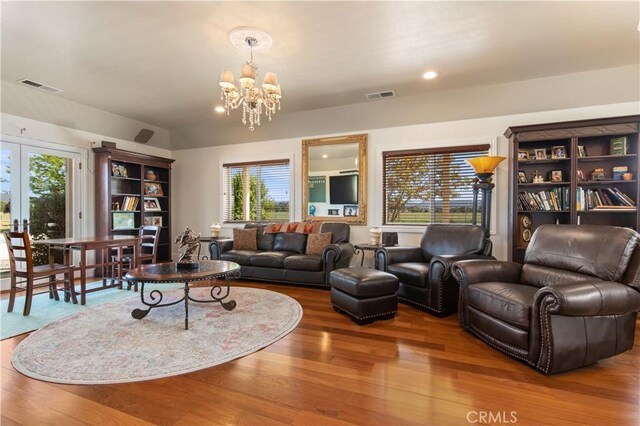 living area with visible vents, a notable chandelier, wood finished floors, and french doors