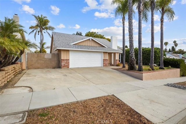 view of front of home featuring a gate, roof with shingles, concrete driveway, a garage, and brick siding