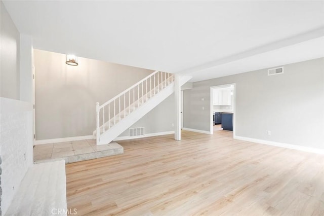 unfurnished living room with visible vents, stairway, baseboards, and wood finished floors