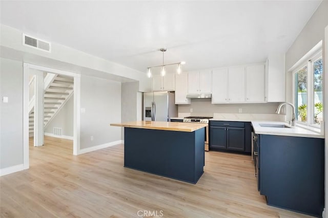 kitchen featuring visible vents, a center island, stainless steel appliances, blue cabinets, and a sink