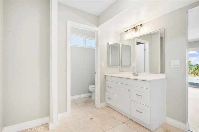 bathroom with tile patterned floors, toilet, vanity, and baseboards