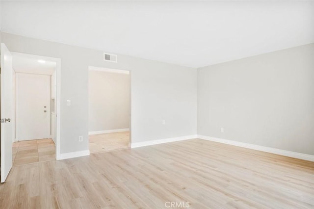 empty room with visible vents, baseboards, and light wood-style floors