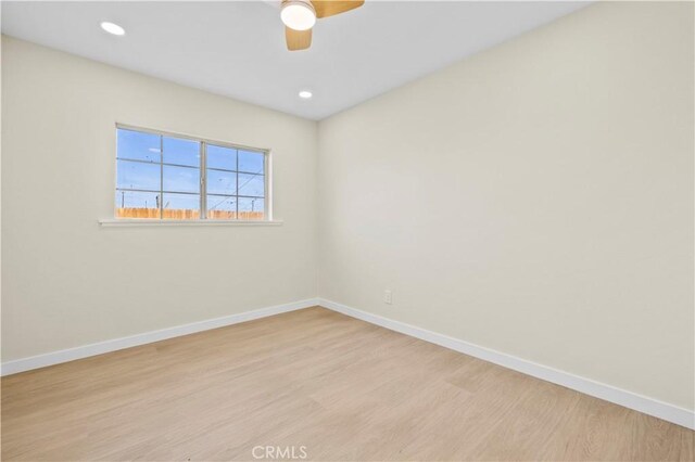 empty room with baseboards, a ceiling fan, and light wood finished floors