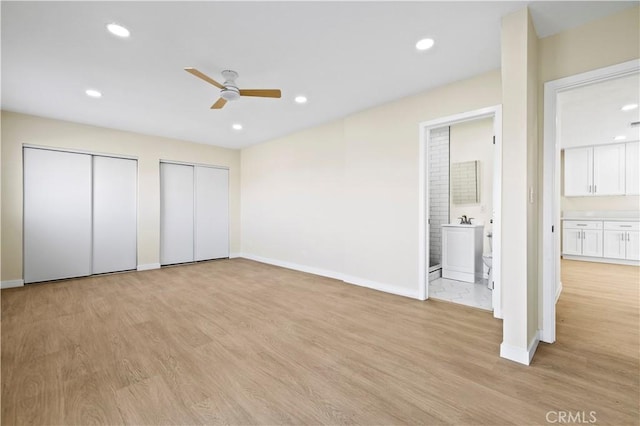 unfurnished bedroom featuring recessed lighting, light wood-type flooring, baseboards, and two closets