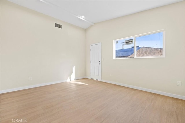 unfurnished room featuring visible vents, baseboards, lofted ceiling, and light wood finished floors