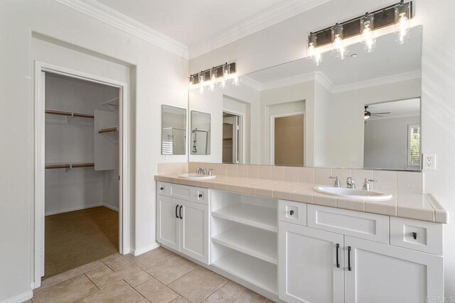 full bath featuring double vanity, a spacious closet, ornamental molding, and a sink