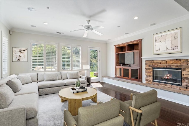 living area with plenty of natural light, a stone fireplace, and crown molding