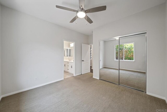 unfurnished bedroom with carpet flooring, baseboards, a closet, and connected bathroom