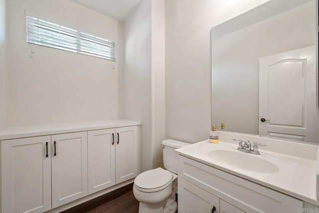 bathroom with toilet, wood finished floors, and vanity