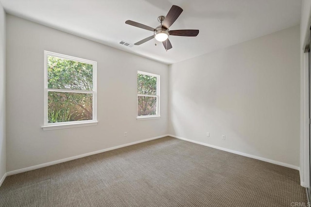 carpeted empty room with visible vents, baseboards, and a ceiling fan