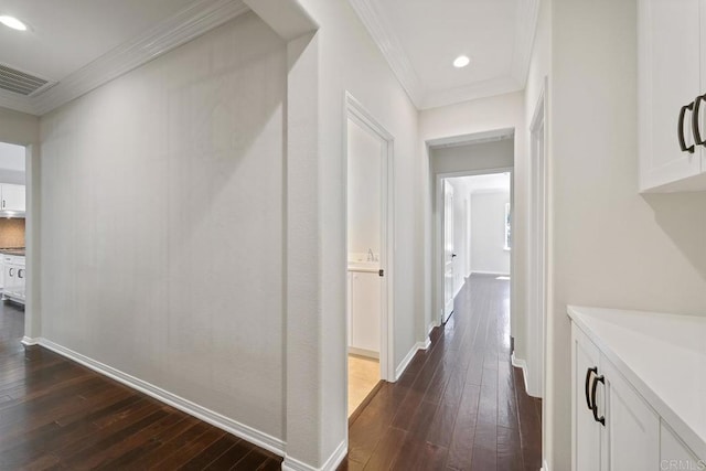 corridor featuring visible vents, baseboards, dark wood-type flooring, and ornamental molding