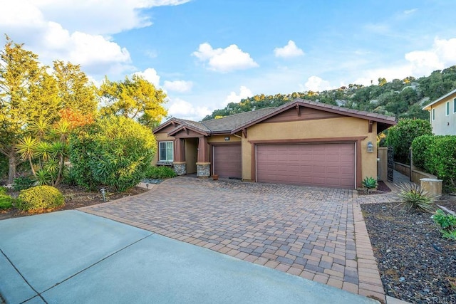 view of front facade with decorative driveway, an attached garage, and stucco siding