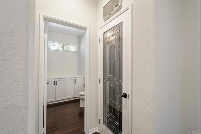 hall featuring dark wood-style floors and a textured wall