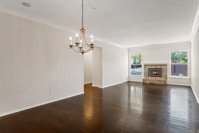 unfurnished living room featuring a stone fireplace, crown molding, dark wood finished floors, and baseboards